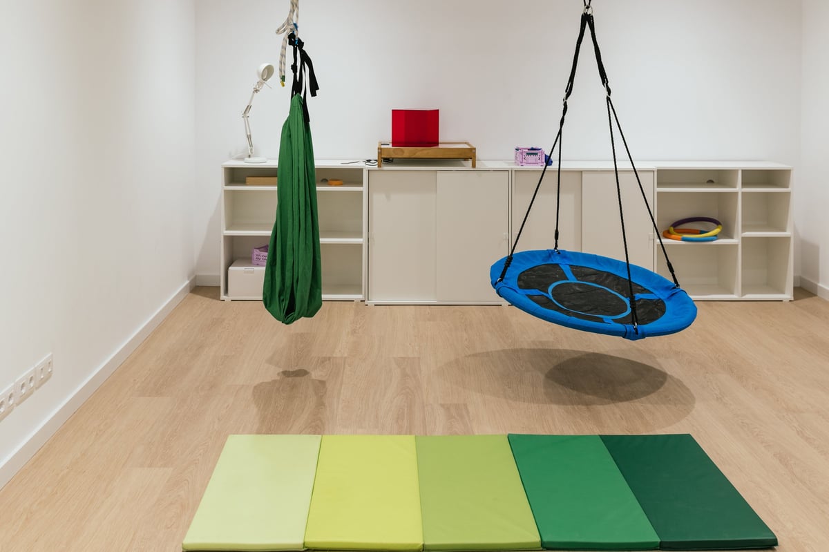Sensory integration therapy room with hanging equipment and colorful mats